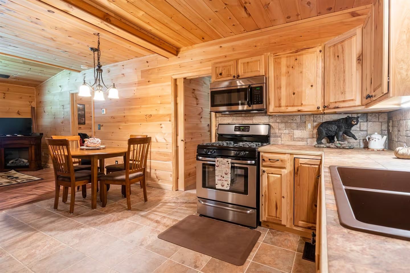 A wooden cabin interior with a kitchen featuring a stove, oven, microwave, and wooden cabinets.