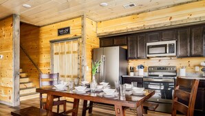 A wooden interior with a dining table set for four, a refrigerator, a microwave, and an oven. - Paws Retreat: 5BR/3BA, Pvt Hot Tub - Sleeps 14 (sevierville)