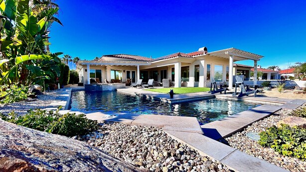 A modern house with a swimming pool, patio furniture, and a well-maintained garden.