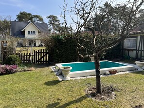 Un patio trasero con piscina, cerca de madera y una casa al fondo.
