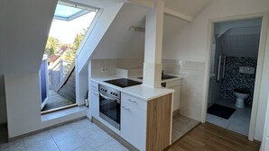 A modern kitchen with a built-in oven and sink, a wooden floor, and a skylight. - Zeuthen, top location, high-quality/quiet/bright furnished top floor apartment with garden, near the lake (Zeuthen)