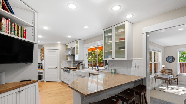 Una cocina moderna con armarios blancos, una isla grande con taburetes y un comedor con mesa y sillas.