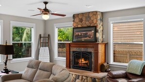 Una sala de estar acogedora con chimenea de piedra, sofás de cuero y ventilador de techo.