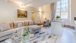 A modern living room with a sofa, coffee table, and dining area. - Luxury 1 Bedroom Apartment with Elevator inside the Walls of Lucca by the Main Square Piazza San Michele (Lucca)
