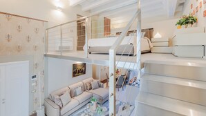 A modern loft bedroom with a bunk bed, a staircase, and a dining area. - Luxury 1 Bedroom Apartment with Elevator inside the Walls of Lucca by the Main Square Piazza San Michele (Lucca)