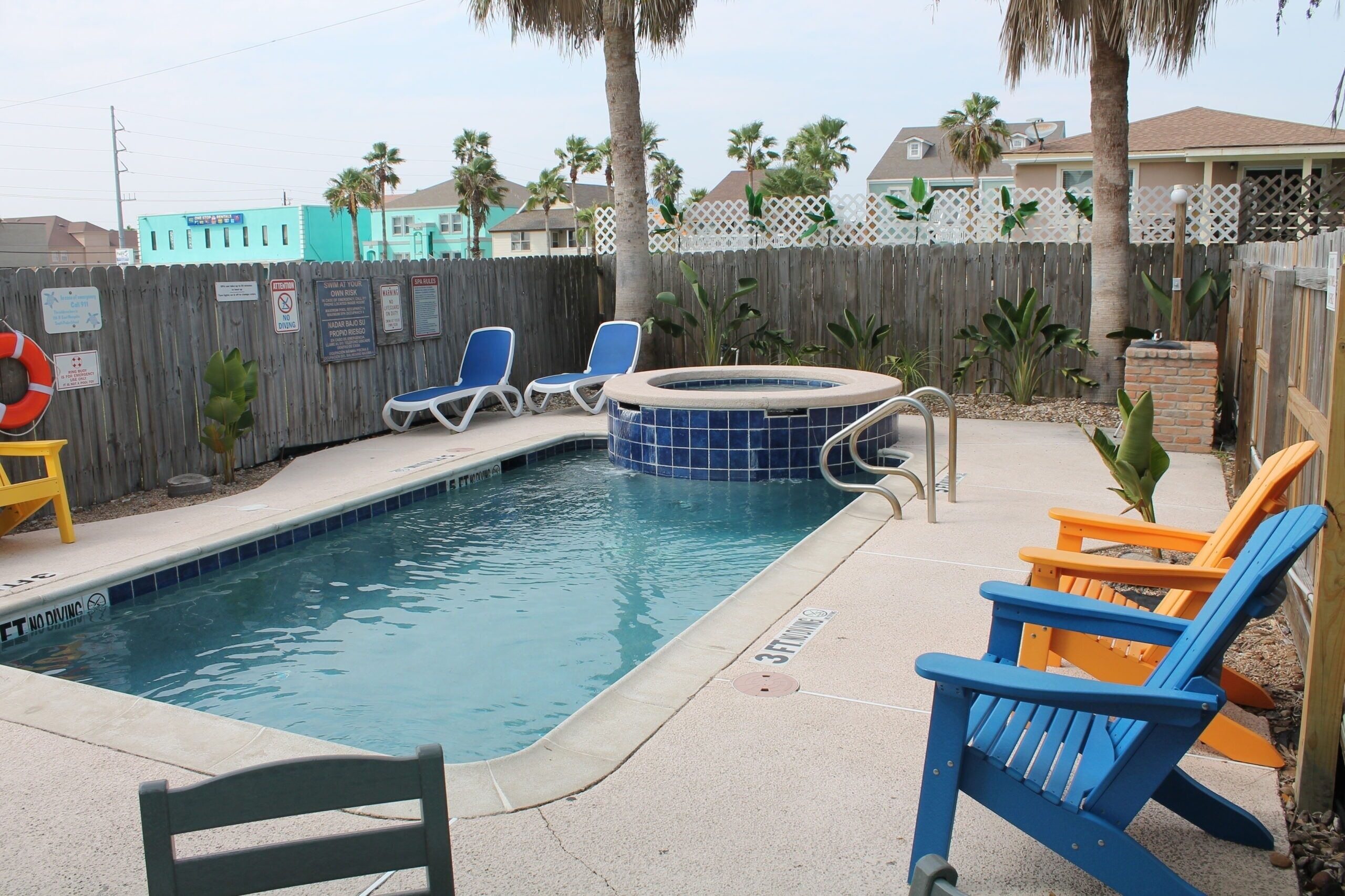 A swimming pool with lounge chairs and a hot tub.