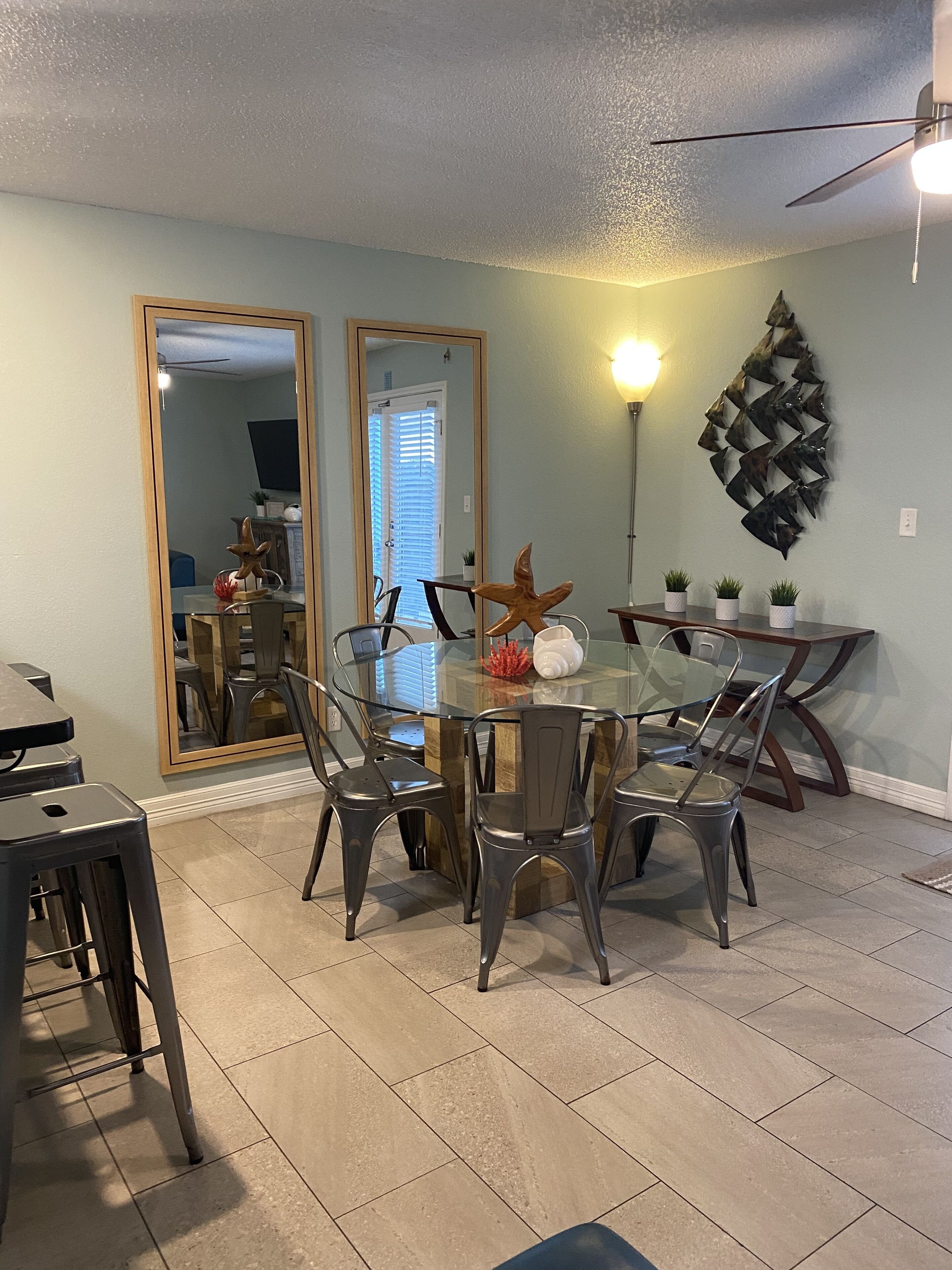 A dining area with a glass-top table, metal chairs, and a decorative starfish centerpiece.