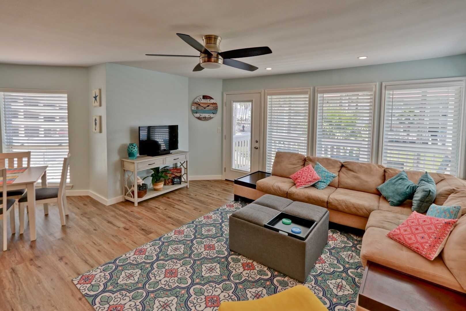 A living room with a sofa, coffee table, TV, and a ceiling fan.