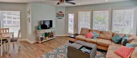 A living room with a sofa, coffee table, TV, and a ceiling fan.