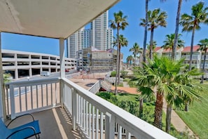 Enjoy breathtaking views of the urban landscape from this balcony with a white railing and a comfortable chair.
