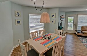 Un comedor con una mesa de madera, sillas y una lámpara colgante.