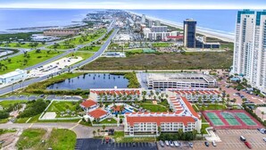 A coastal cityscape with a marina, a large hotel with red roofs, and high-rise buildings. - Gulfpoint 3209 2 Bedroom Condo by RedAwning (South Padre Island)