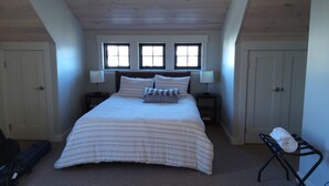 A bedroom with a large bed, two bedside tables with lamps, a window, and a door.