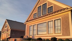 A two-story house with a sloped roof, large windows, and a well-maintained lawn.