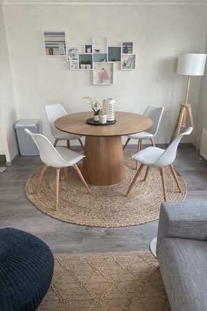 A dining area with a round table, four chairs, a woven rug, and wall-mounted artwork. - Lovely Beach House for 4 persons within walking distance from the Beach  (Breskens)