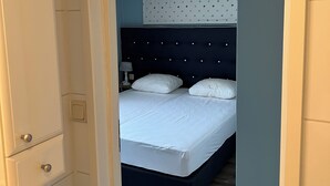 A bedroom with a dark blue headboard, white bedding, and a wooden floor. - Lovely Beach House for 4 persons within walking distance from the Beach  (Breskens)