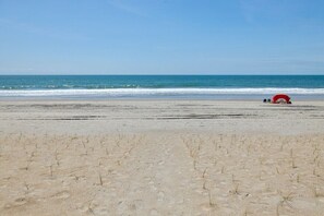 Una playa con una estructura parecida a una carpa roja a lo lejos.