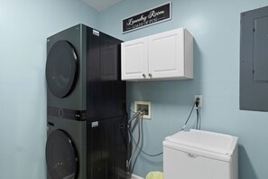 A laundry room with a washer, dryer, and a cabinet labeled 'Laundry Room Loads of Fun.'