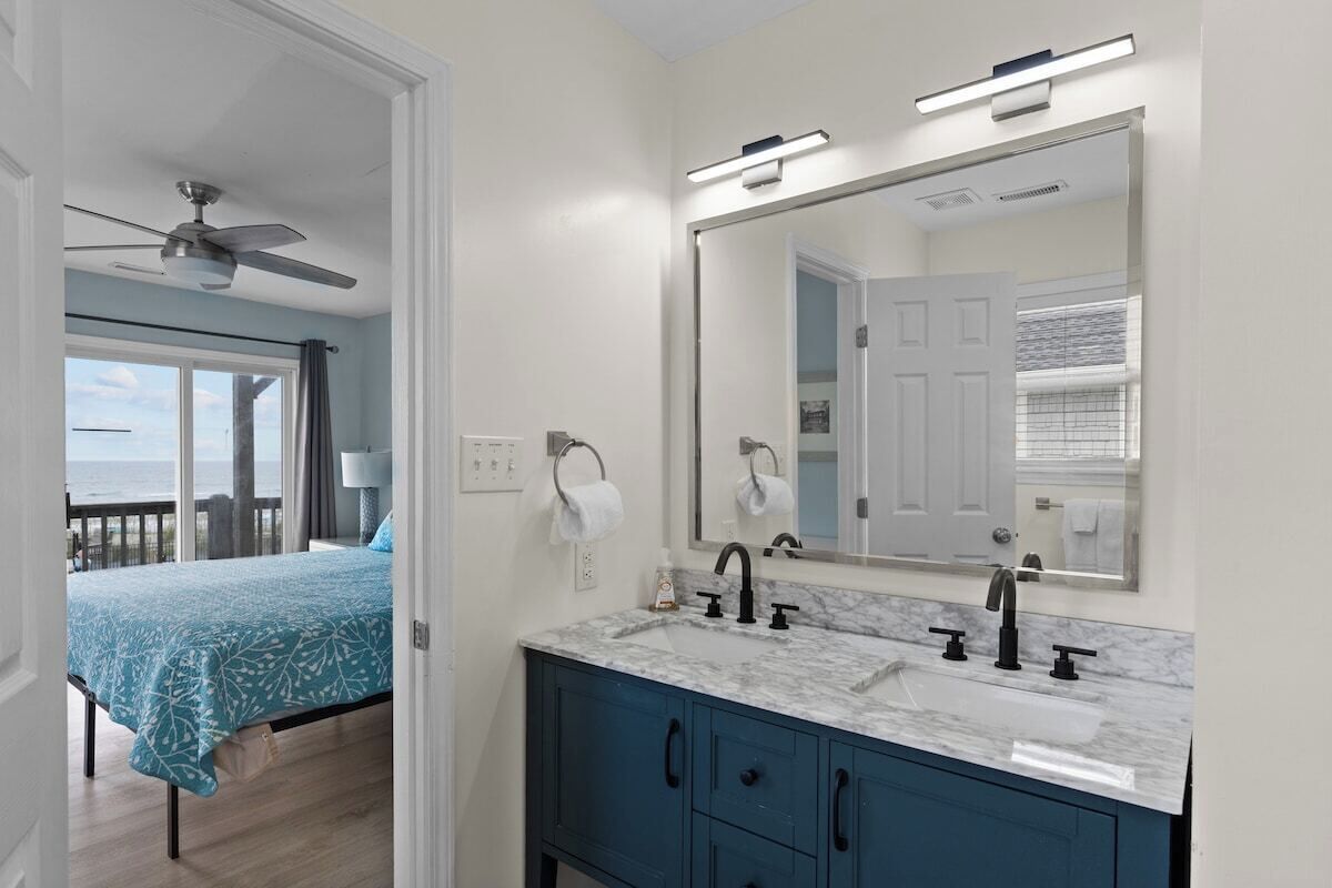 A bedroom with a bed, a bathroom with a sink and mirror, and a balcony with a view.