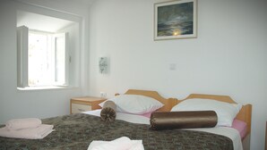 Ein Schlafzimmer mit einem Bett, einem Nachttisch, einem Fenster und einem Gemälde an der Wand.