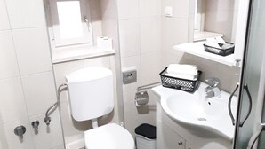 Ein kleines Badezimmer mit Toilette, Waschbecken und Dusche.