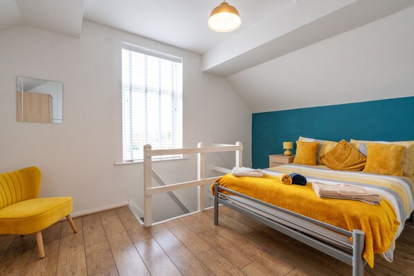 Un dormitorio con cama, una silla, un ventanal y una lámpara de techo.