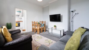 Ein modernes Wohnzimmer mit einer Couch, einem Couchtisch und einem an der Wand befestigten Fernseher.