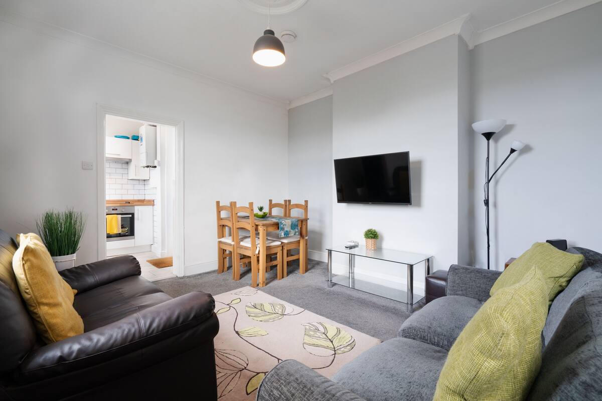 Ein modernes Wohnzimmer mit einer Couch, einem Couchtisch und einem an der Wand befestigten Fernseher.