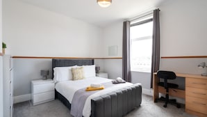 Ein Schlafzimmer mit Bett, Nachttischen, Schreibtisch und Stuhl.
