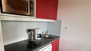 Cocina compacta con microondas, cafetera y lavabo.