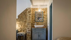 A bathroom with a stone wall, a sink with a decorative mirror, and a patterned floor.