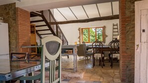 A rustic dining area with a stone floor, wooden furniture, and a brick fireplace.