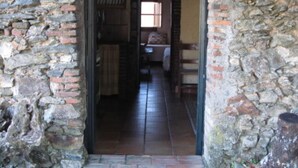 Un estrecho arco de piedra que da paso a una habitación con cama y ventana.