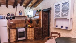 Una cocina rústica con estufa, ollas colgantes y una mesa de madera.