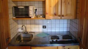 Cocina pequeña con microondas, fregadero y estufa.