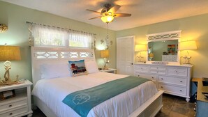 A bedroom with a bed, nightstands, a dresser, a mirror, and a ceiling fan.