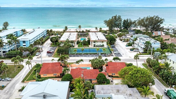 A resort with a tennis court, pool, and ocean view.