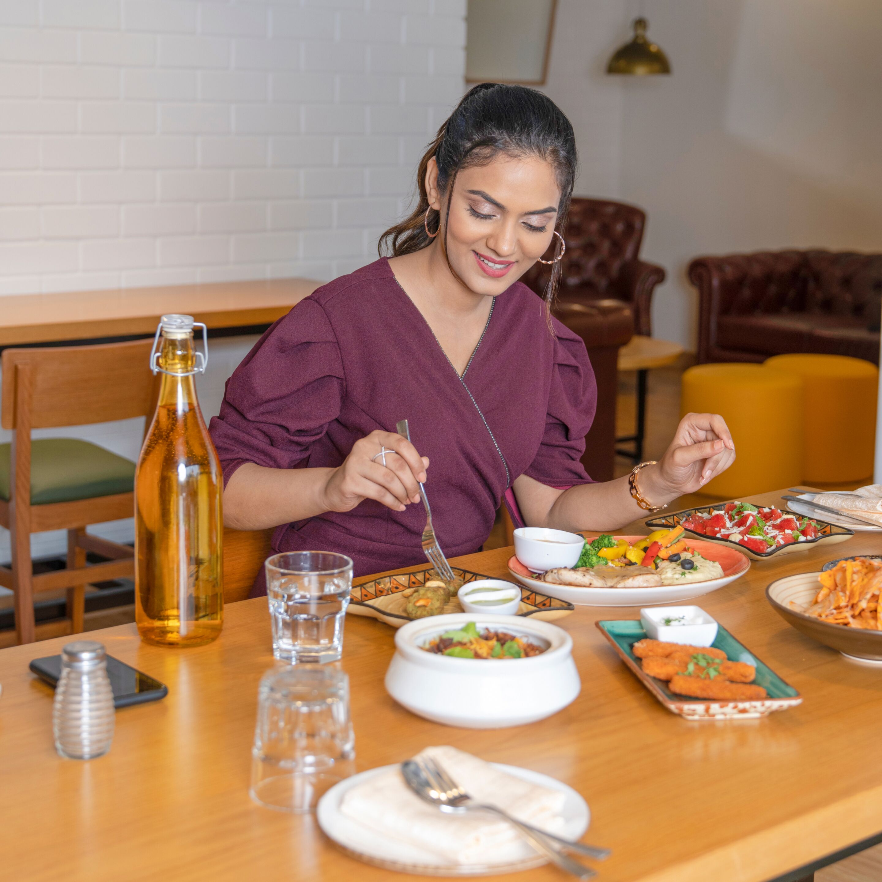 A dining table with various dishes, a bottle, glasses, and a smartphone.