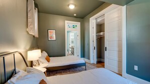 A bedroom with two beds, a bedside table with a lamp, a framed picture on the wall, and a door leading to a closet. - East Nash 3BR Fenced Yard | Deck | Parking | Pets (Nashville)