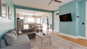 A modern living room with a gray sofa, a coffee table, and a TV mounted on the wall. - East Nash 3BR Fenced Yard | Deck | Parking | Pets (Nashville)