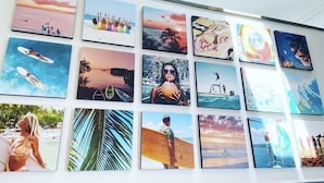 A wall with multiple framed pictures depicting various beach scenes and water activities.