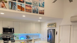 A modern kitchen with white cabinets, a central island, and a dining area with light blue chairs.