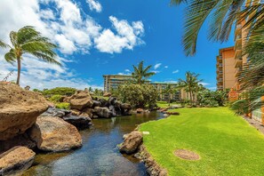 A landscaped area with a water feature, palm trees, and a building with multiple balconies.