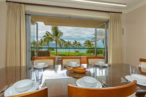 Enjoy meals with a view of the tropical landscape from this dining area, featuring a large oval-shaped table and glass partition.