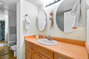 A bathroom with a wooden vanity, a white sink, a mirror, and a towel hanging on the wall.