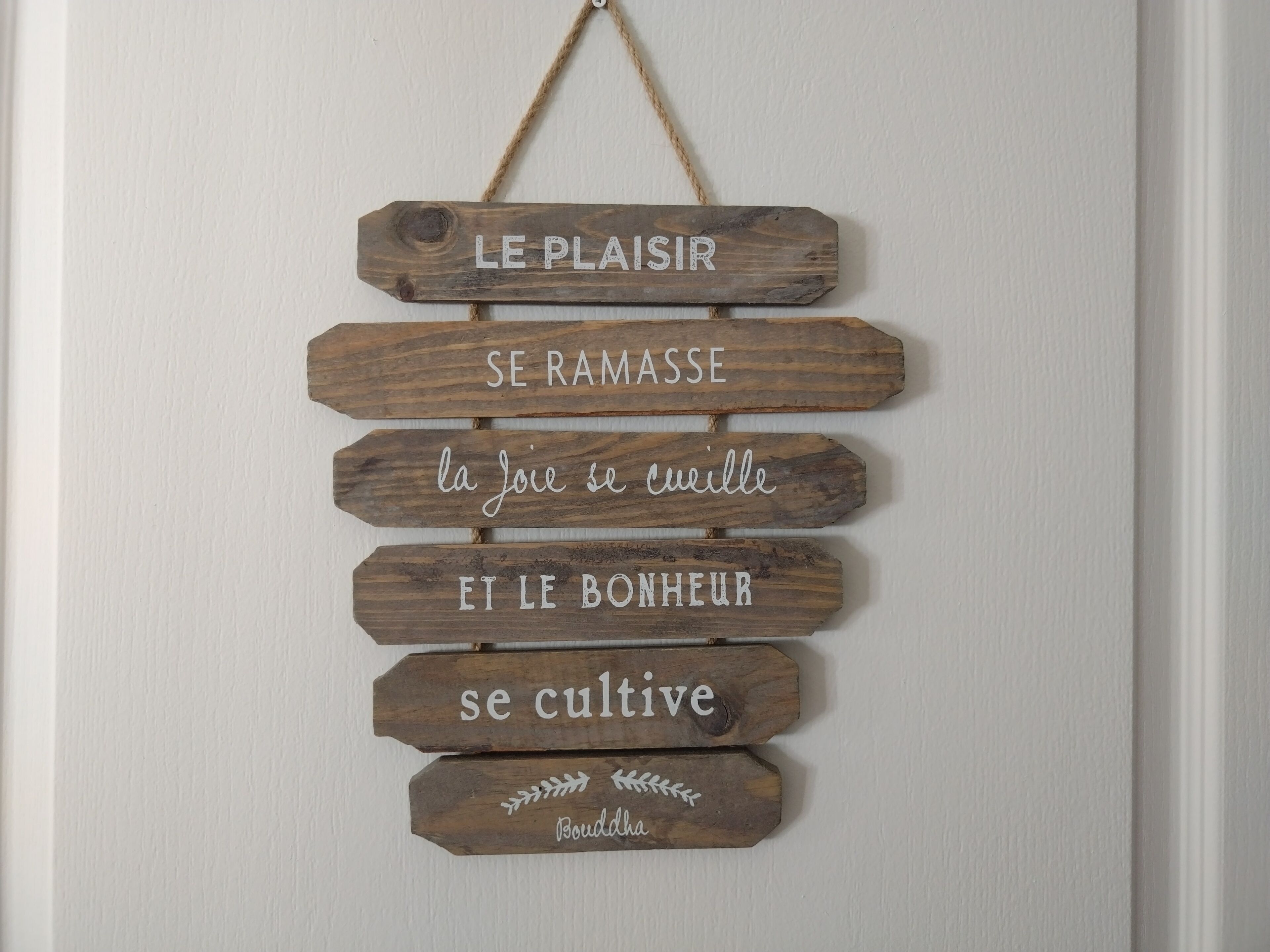 A wooden sign with French phrases.