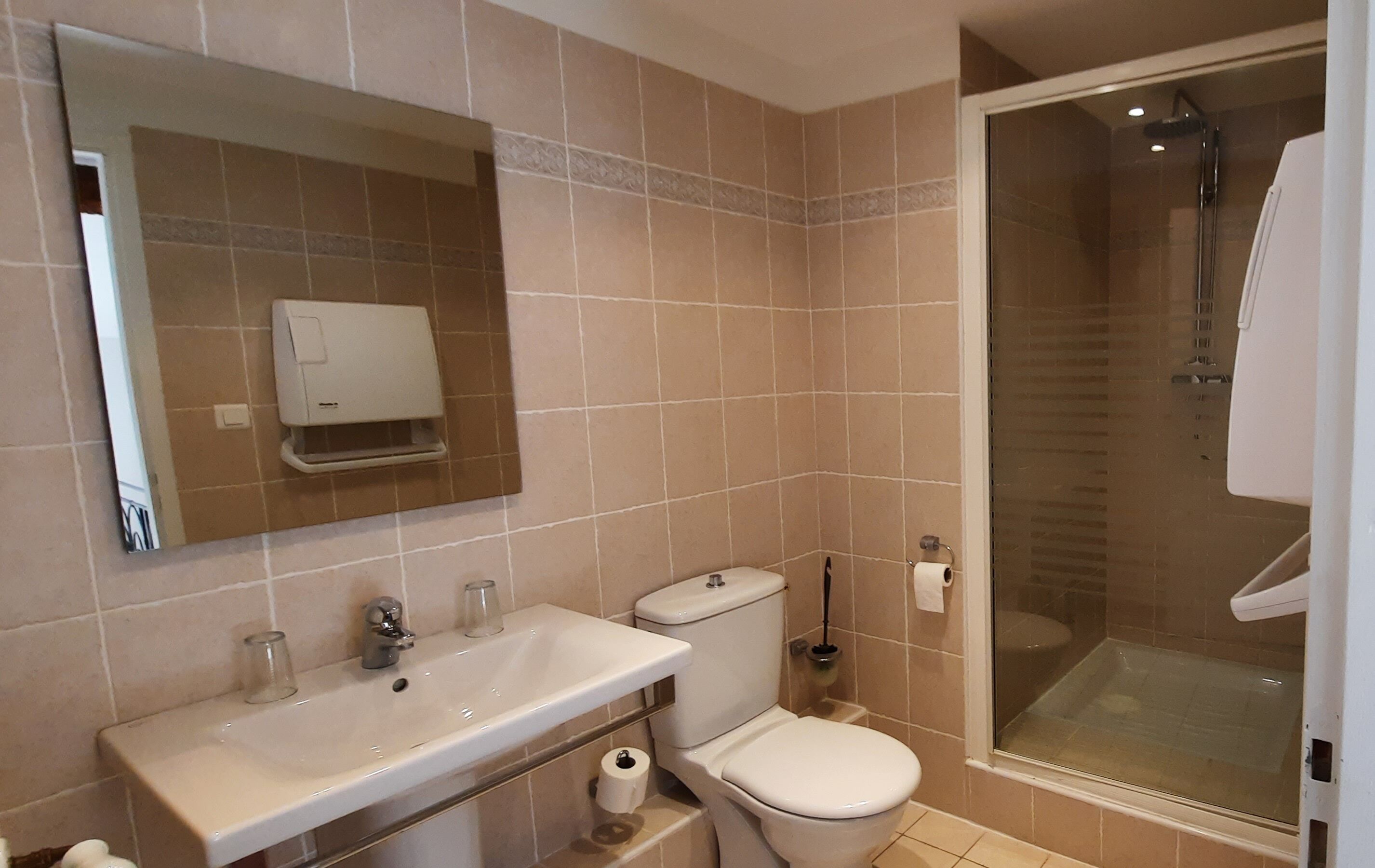 Un baño con lavamanos, inodoro y ducha con mampara de vidrio.