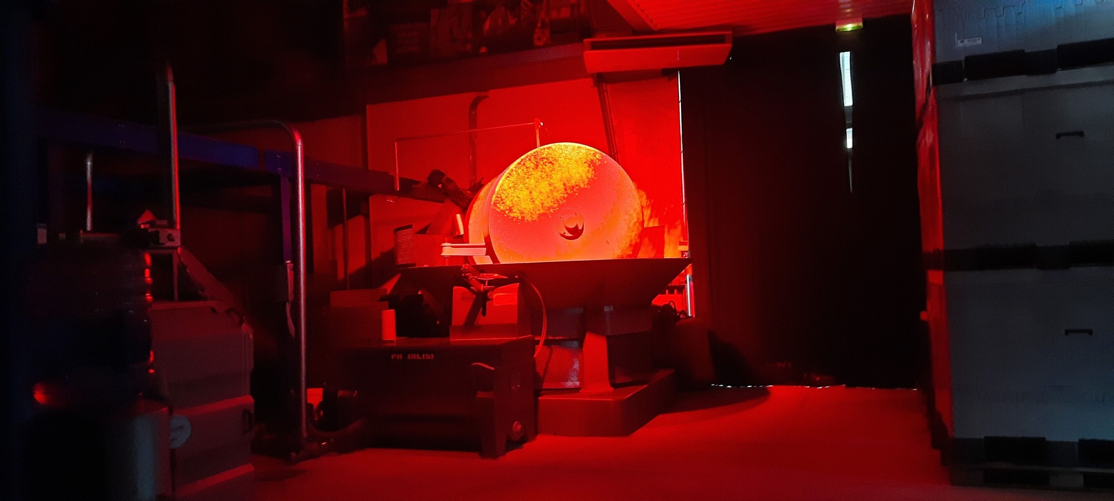A room with a large spherical object in the center, surrounded by various equipment and a red-lit environment.