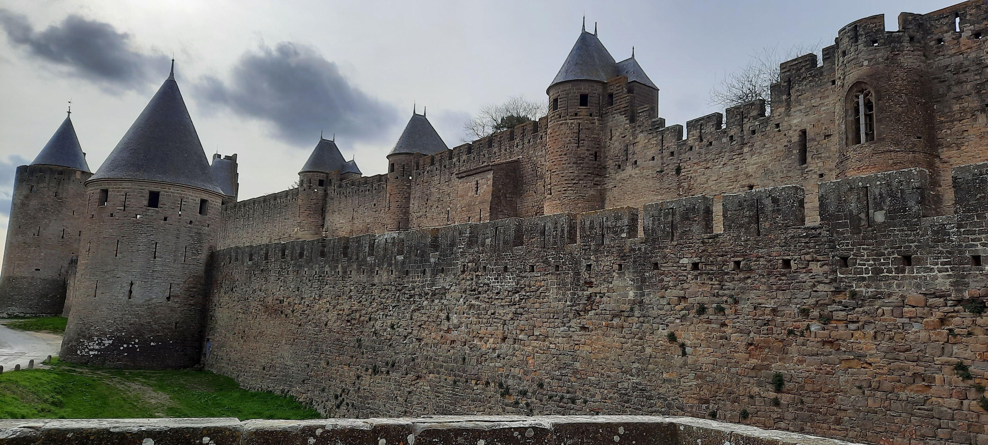 Een middeleeuws kasteel met meerdere torens en een dikke stenen muur.