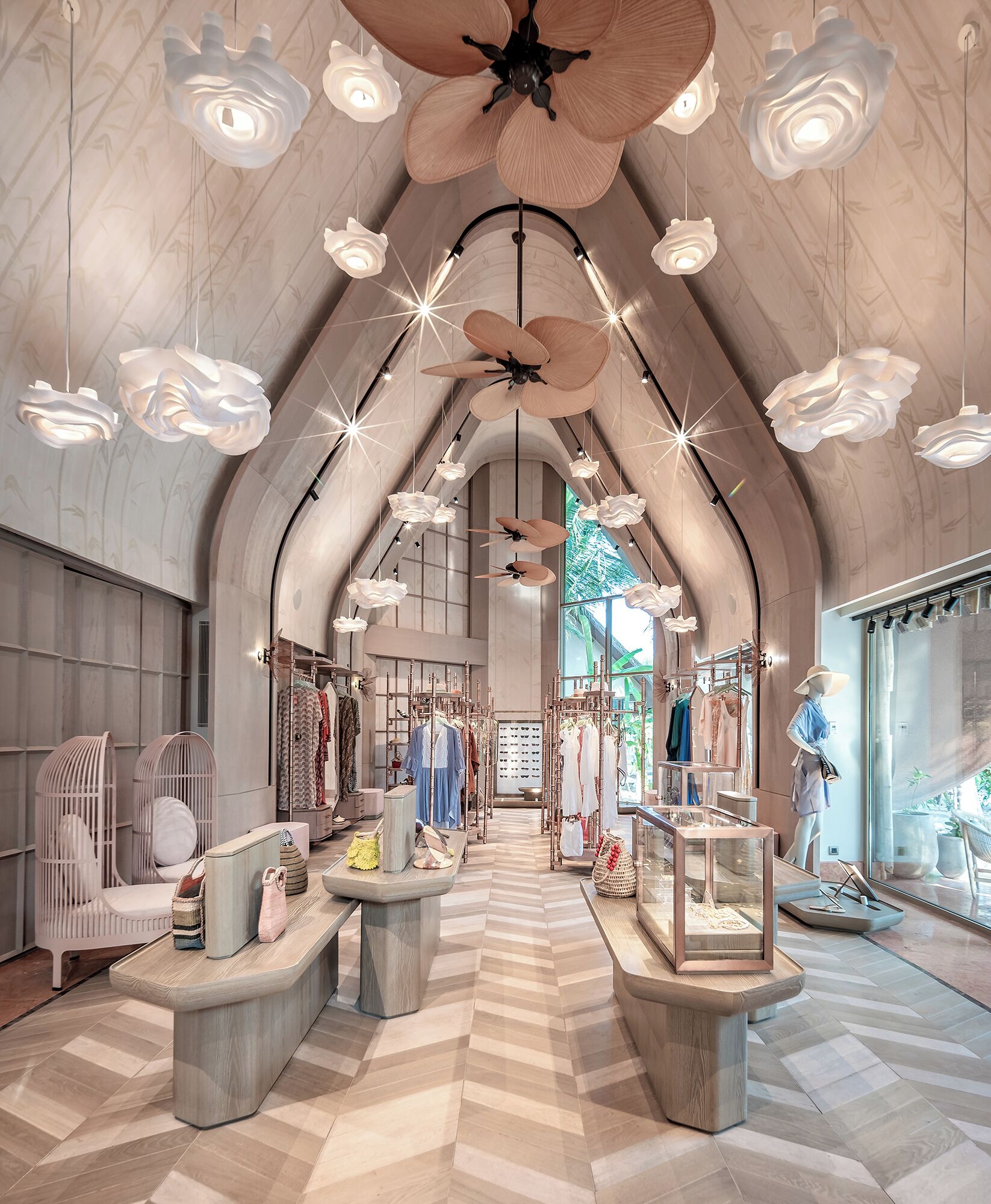 Una boutique espaciosa con techo alto, vigas de madera y un pasillo central que conduce a un gran ventanal.